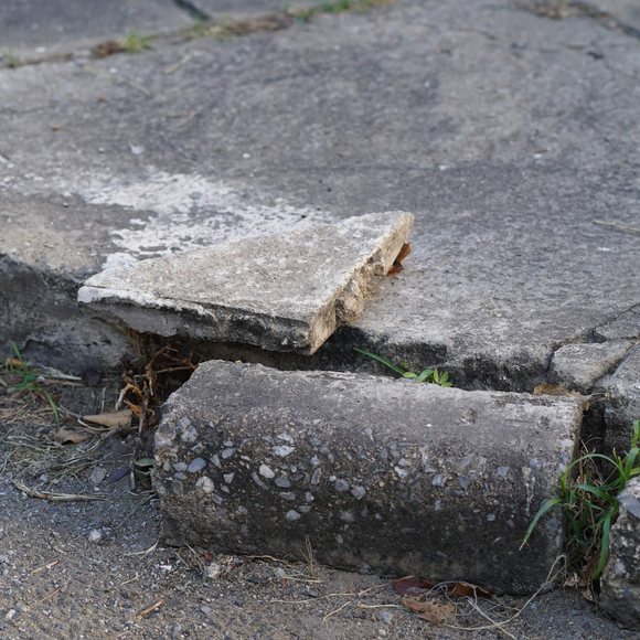 Trip hazards Cracked and uneven sidewalk slab forming a trip hazard